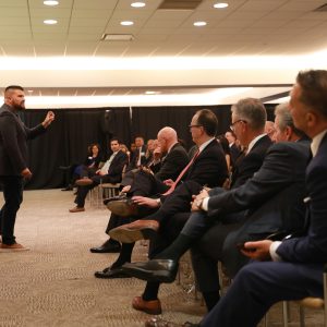 audience in business clothing in a large room listening to a presentation